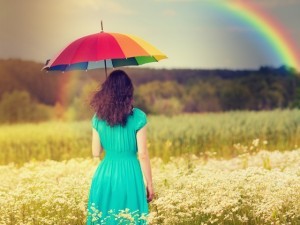 Young woman walking on the field under umbrella in fair weather