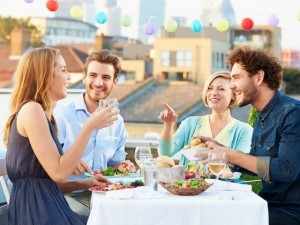 Group Of Friends Eating Meal On Rooftop Terrace