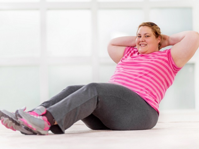 Smiling young woman doing sit-ups and looking at camera.