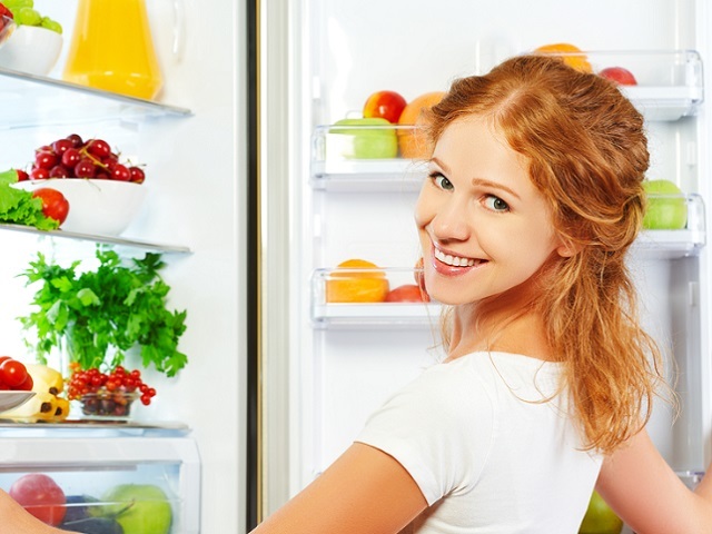 Happy woman and open refrigerator with fruits, vegetables and he